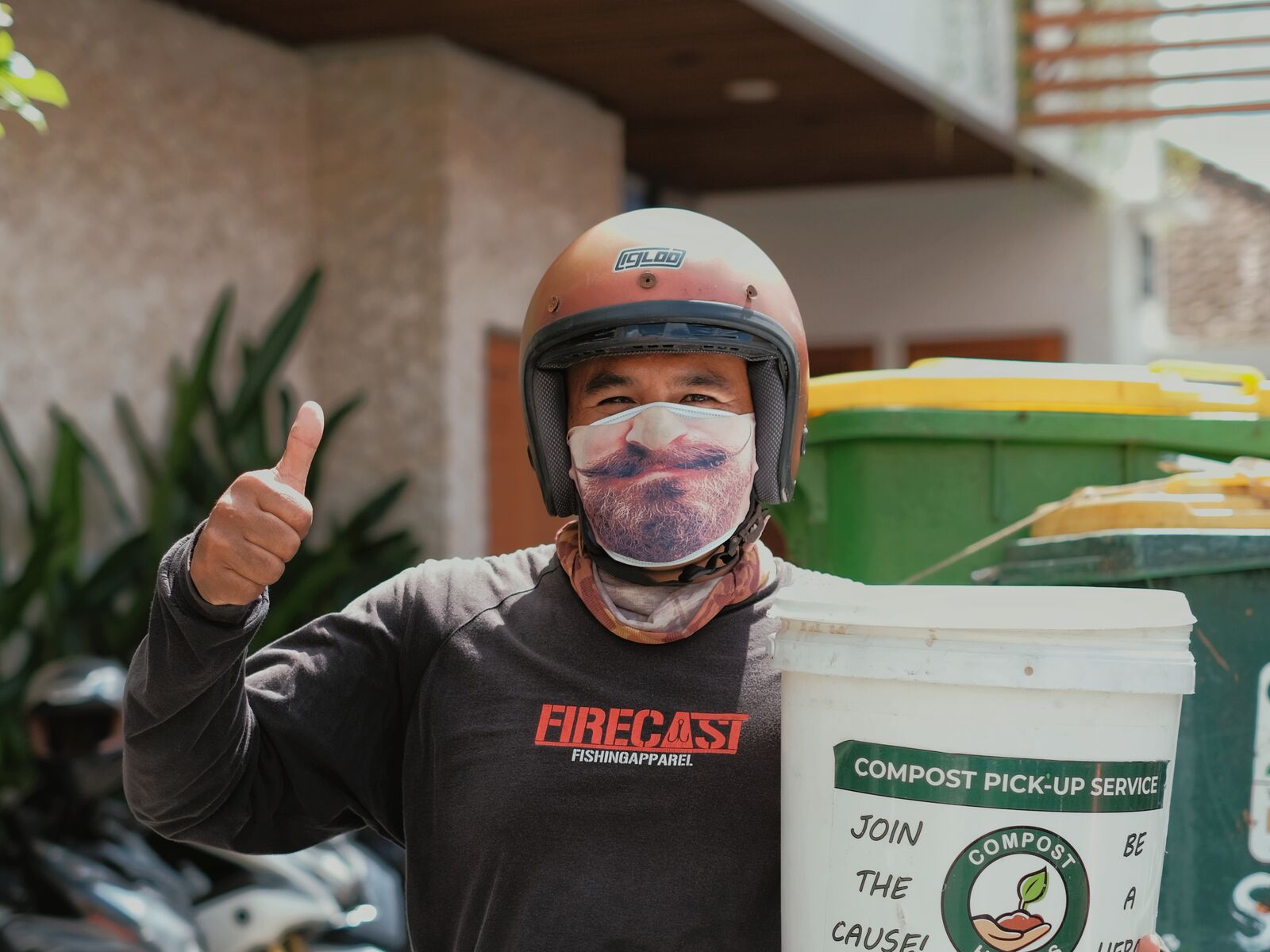 A Compost Heroes collector giving a thumbs up with a pick-up bucket.