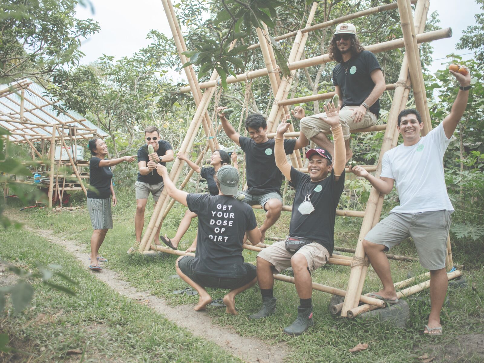 The Jiwa team laughing and posing on a bamboo frame in the garden.